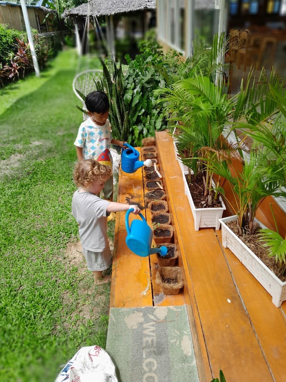 Children watering plants in garden
